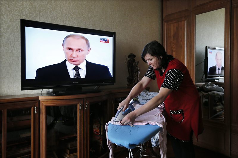 Рускиня домакинства, докато  Путин говори пред руския парламент, сн. ЕПА/БГНЕС