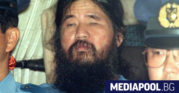 Шоко Асахара ескортиран от двама полицаи през септември 1995 година