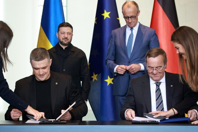 Германският министър на отбраната Борис Писториус (вдясно) и министърът на отбраната на Украйна Михайло Федоров (вляво) подписват германо-украинско споразумение за сътрудничество в областта на отбраната в присъствието на германския канцлер Фридрих Мерц (в