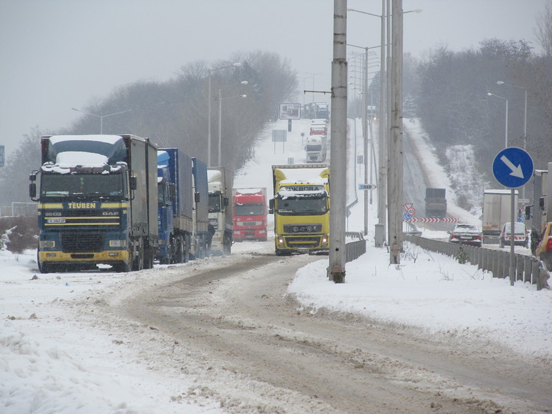 Тапи на кръговото кръстовище край Дунав мост и в района на международния булевард "България" в Русе затрудниха движението на автомобили. При излизането си от паркингите тежкотоварните камиони буксуват, а други тирове искат да влязат на тяхно място. В задръстването попаднаха и част от снегопочистващите машини. Снимка: БГНЕС