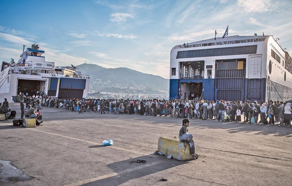 Бежанци на остров Лесбос чакат, за да бъдат откарани във вътрешността на страната.