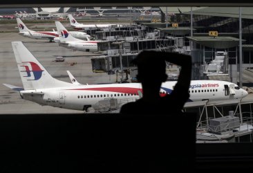 Пътник на летището в Куала Лумпур гледа към самолети на "Малайжа Еър", сн. ЕПА/БГНЕС
