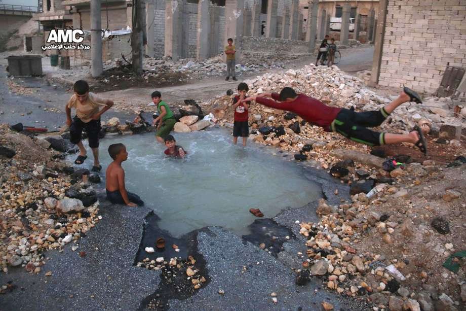 Деца се гмуркат в пълна с вода дупка от ракетна атака в Алепо