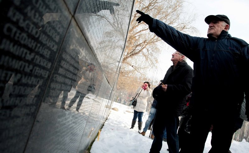 <i>Мъже търсят името на свой близък, изписано на Мемориала на жертвите на комунизма край НДК в столицата на 1 февруари. Сн: БГНЕС</i>