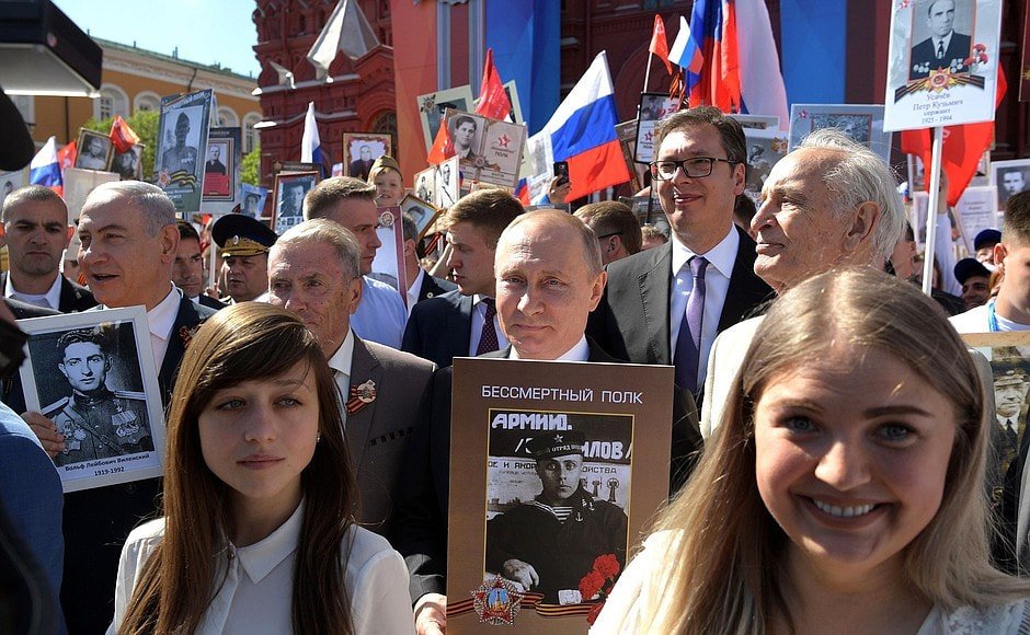 Владимир Путин (в средата със снимка в ръце) по време на днешната акция "Безсмъртният полк" в Москва. Редом до него са министър-председателят на Израел Бенямин Нетаняху (крайно ляво, също със снимка в ръце) и президентът на Сърбия Александър Вучич (дясно зад Путин).