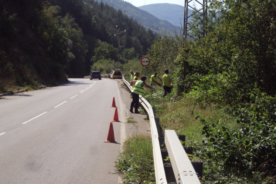 Работници разчистват избуялата трева по пътя край Своге. В това положение са повечето от пътищата в България, а на места тревата е превзела асфалта