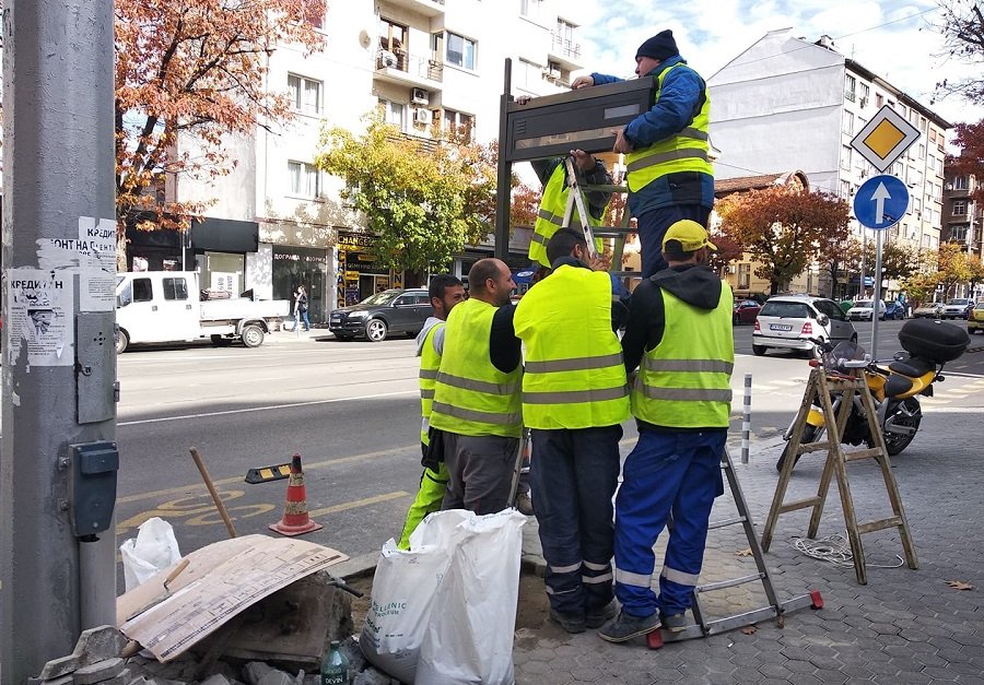 Шестима работници монтират едно от новите табла за градския транспорт в София. За целта те махнаха част от настилката от тротоара на бул. Дондуков". Този участък беше ремонтиран основно само преди година. Сн. Mediapool