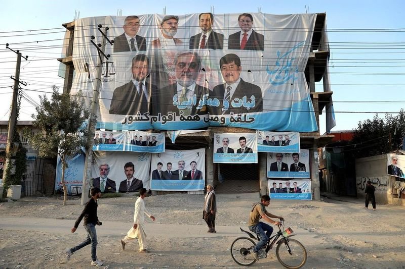 Афганистанци преминават покрай предизборните плакати на един от основните кандидати за президент - Абдула Абдула