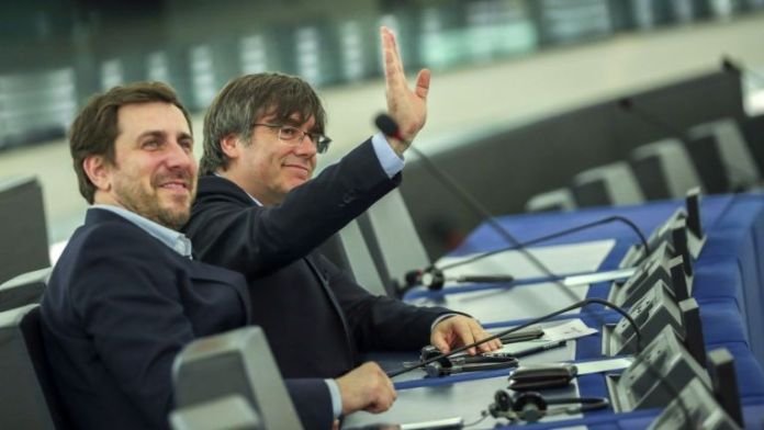 Карлес Пучдемон (махащият с ръка) и Антони Комин в залата на Европарламента в понеделник