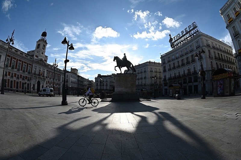 Разносвач на храна минава с велосипед през празния площад Пуерта дел Сол в Мадрид