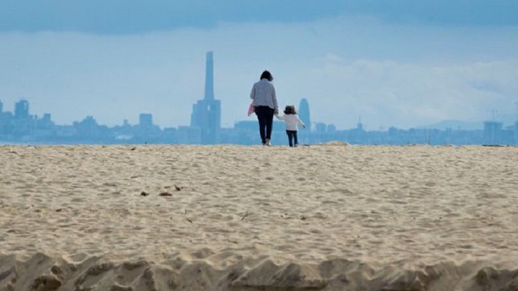 Жена и дете се разхождат във вторник на плажа Ел Масноу северно от Барселона