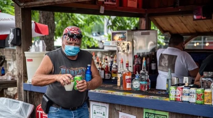Мъж с маска носи напитки в бар в Остин, щата Тексас