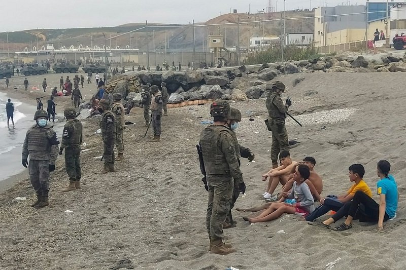 Испански военни наблюдават група мигранти на брега в Сеута