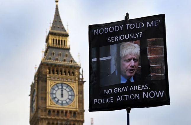 Протестиращ държи плакат пред британския парламент за оставка на премиера Борис Джонсън. Снимка: ЕПА/БГНЕС