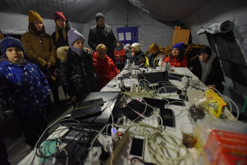 Хората зареждат устройствата си от електрогенератор в отоплителен пункт, организиран от държавната служба за извънредни ситуации, по време на прекъсване на тока в Киев, Сн. ЕПА/БГНЕС