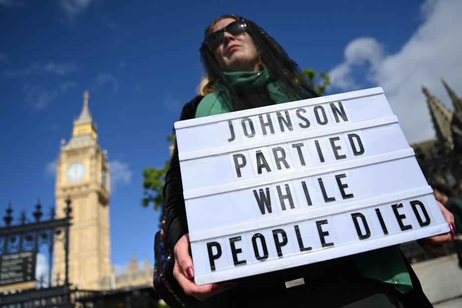 Жена държи плакат с надпис "Джонсън празнуваше докато хората умираха". ЕПА/БГНЕС