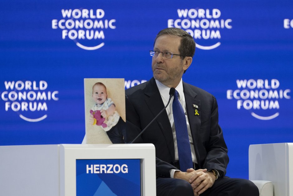 Израелският президент Исаак Херцог говори по време на Световния икономически форум в Давос, а до него беше поставена снимка на бебето Кфир Бибас, взето за заложник от Хамас, Сн. ЕПА/БГНЕС