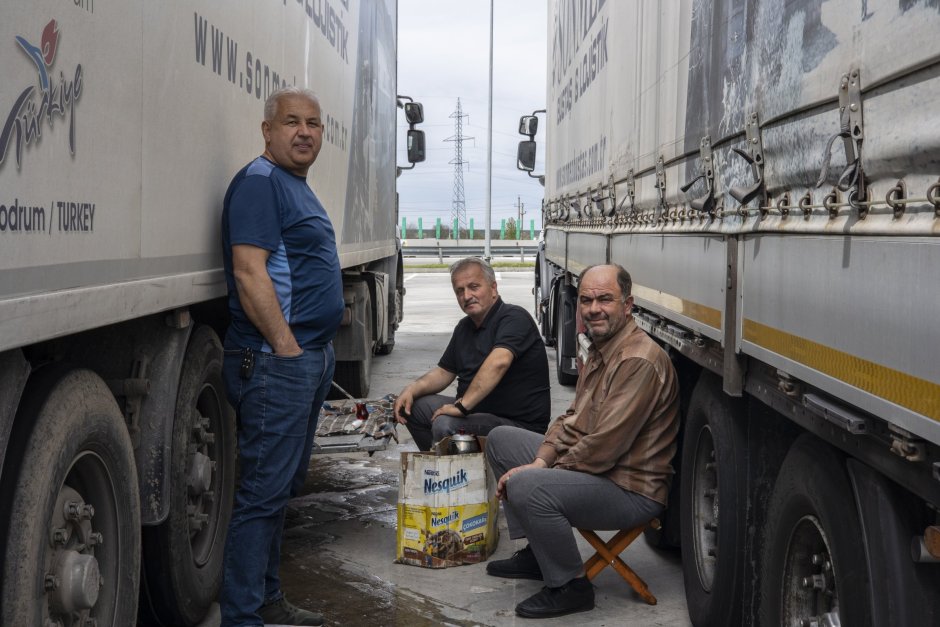 Турските шофьори на камиони Аднам и Сабан, които транспортират автомобилни части от Турция до Франция и Холандия, почиват на сянка на камиона си близо до границата между Румъния и България на 4 април. Снимка Lola García-Ajofrín/El Confidencial/PULSE