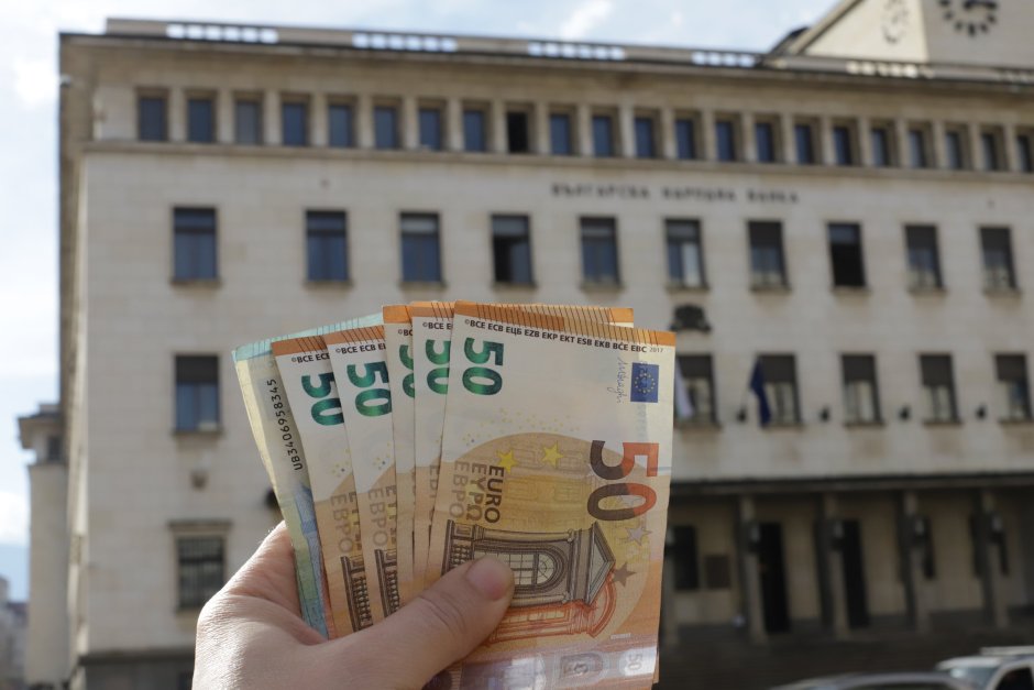 Човек държи банкноти евро пред сградата на Българската народна банка. БГНЕС